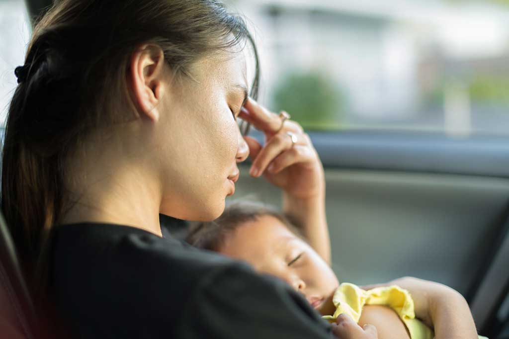 Exhausted mother with sleeping infant.