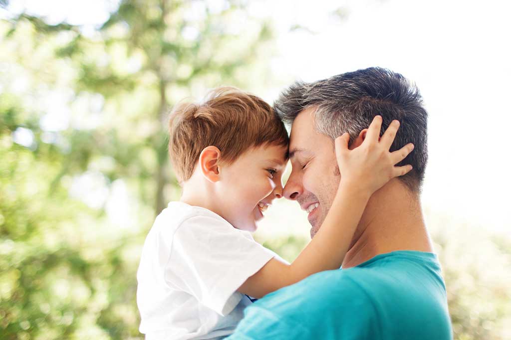 Father with young son facing each other smiling