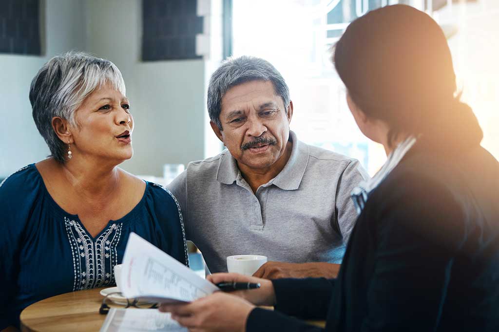 Spanish speaking middle aged couple discuss options with bilingual attorney