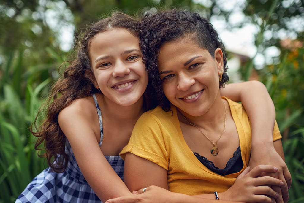 Young 12 year old girls with arm around mother.
