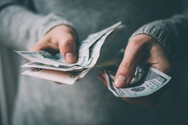 Hands holding different currency bills